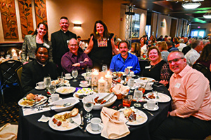 a large group poses at a gala with several plates of food