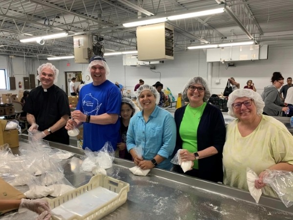 a group with hair nets putts flour into bags in a clean facility