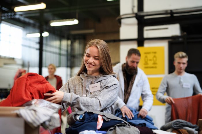 Portrait of volunteers sorting out donated clothes in community charity donation center