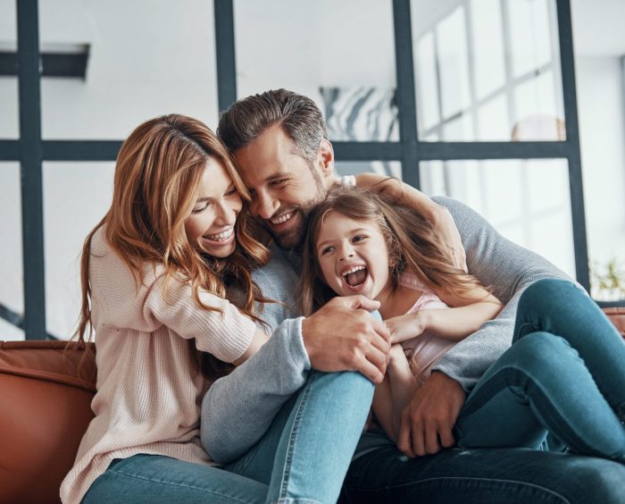 Happy young family smiling and embracing while bonding together at home