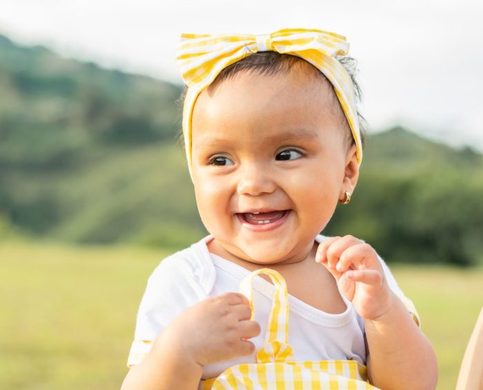 smiling baby in an outdoor field on a summer day