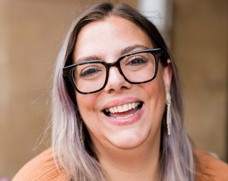 woman with glasses smiling and laughing looking at camera