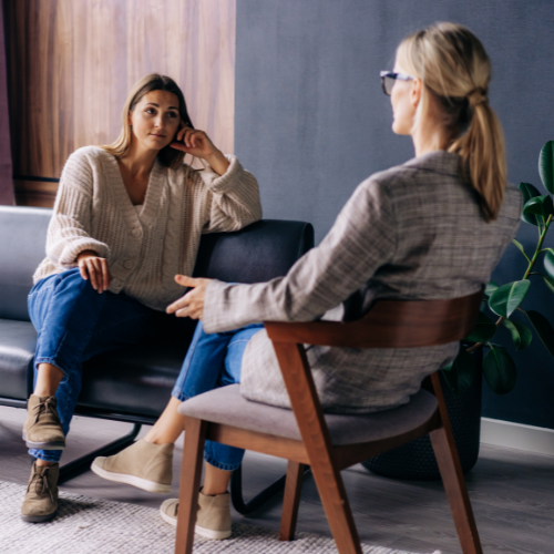 woman and professional sitting and talking in an office