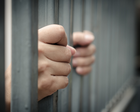 person holding bars in jail