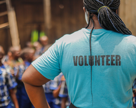 woman with volunteer t-shirt standing with her back towards the camera