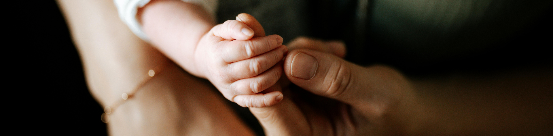 baby holding womans fingers