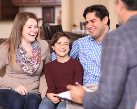 family of there sitting down smiling during counseling session
