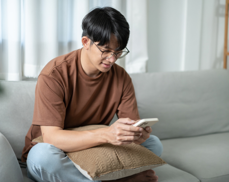 Young Man Sitting On Couch And Looking At Phone